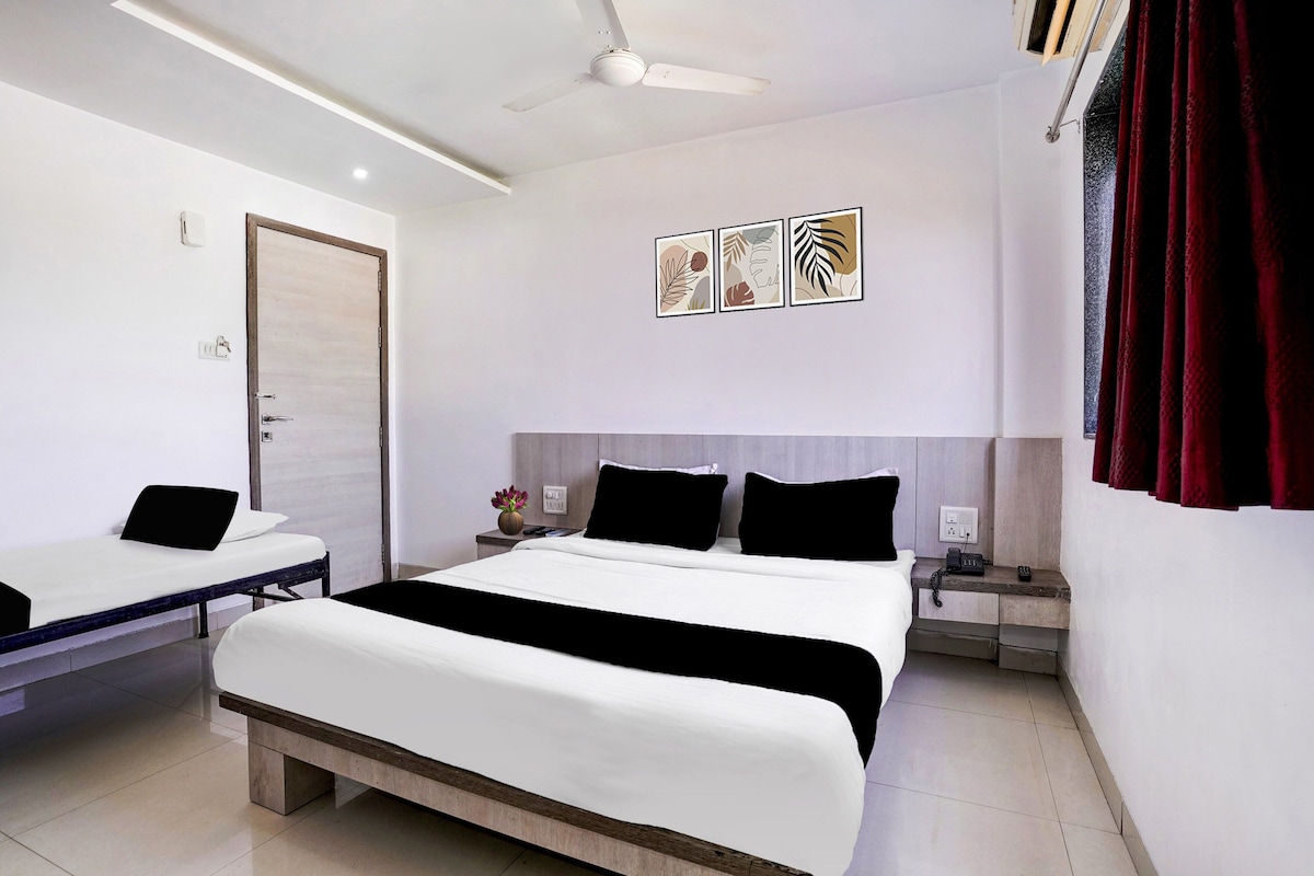 Une chambre d’hôtel avec un lit, des tables de chevet, un ventilateur de plafond et une porte.