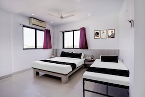 Une chambre d’hôtel moderne avec deux lits, un ventilateur de plafond et une fenêtre avec des rideaux.