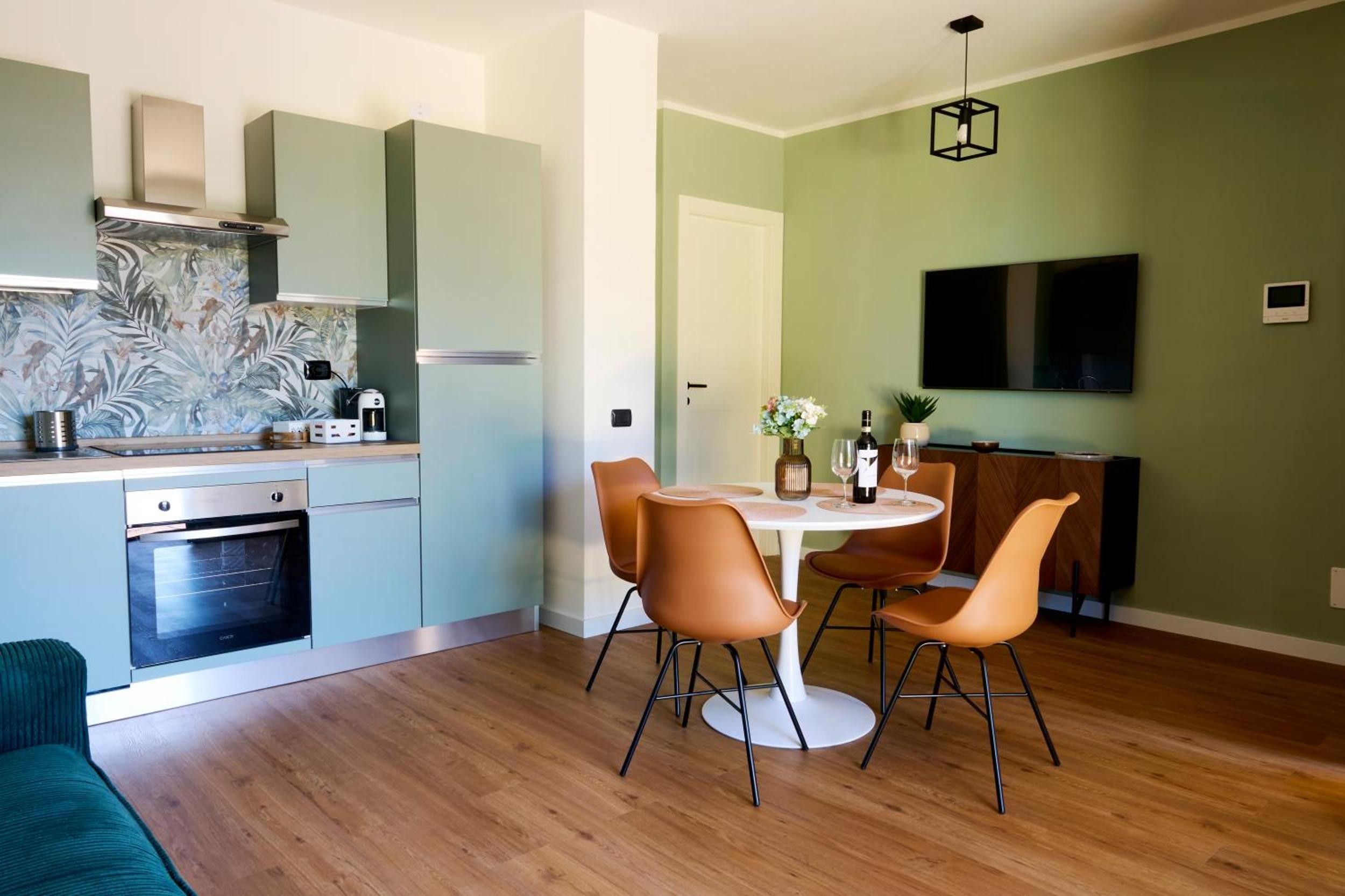Una cucina moderna con forno integrato, macchina del caffè e microonde. È presente un'area pranzo con un tavolo rotondo e quattro sedie.