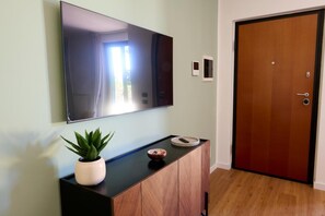 A room with a flat-screen TV mounted on the wall, a wooden cabinet with a potted plant, a small bowl, and a door with a lock. - Apartment 'Casa Mimma' with Private Terrace, Wi-Fi and Air Conditioning (Terni)