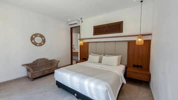 Een slaapkamer met een bed, nachtkastjes, een houten hoofdbord, een wandairconditioner en een hanglamp.