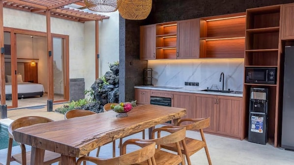 A modern kitchen with wooden cabinets, a marble countertop, and a built-in microwave.