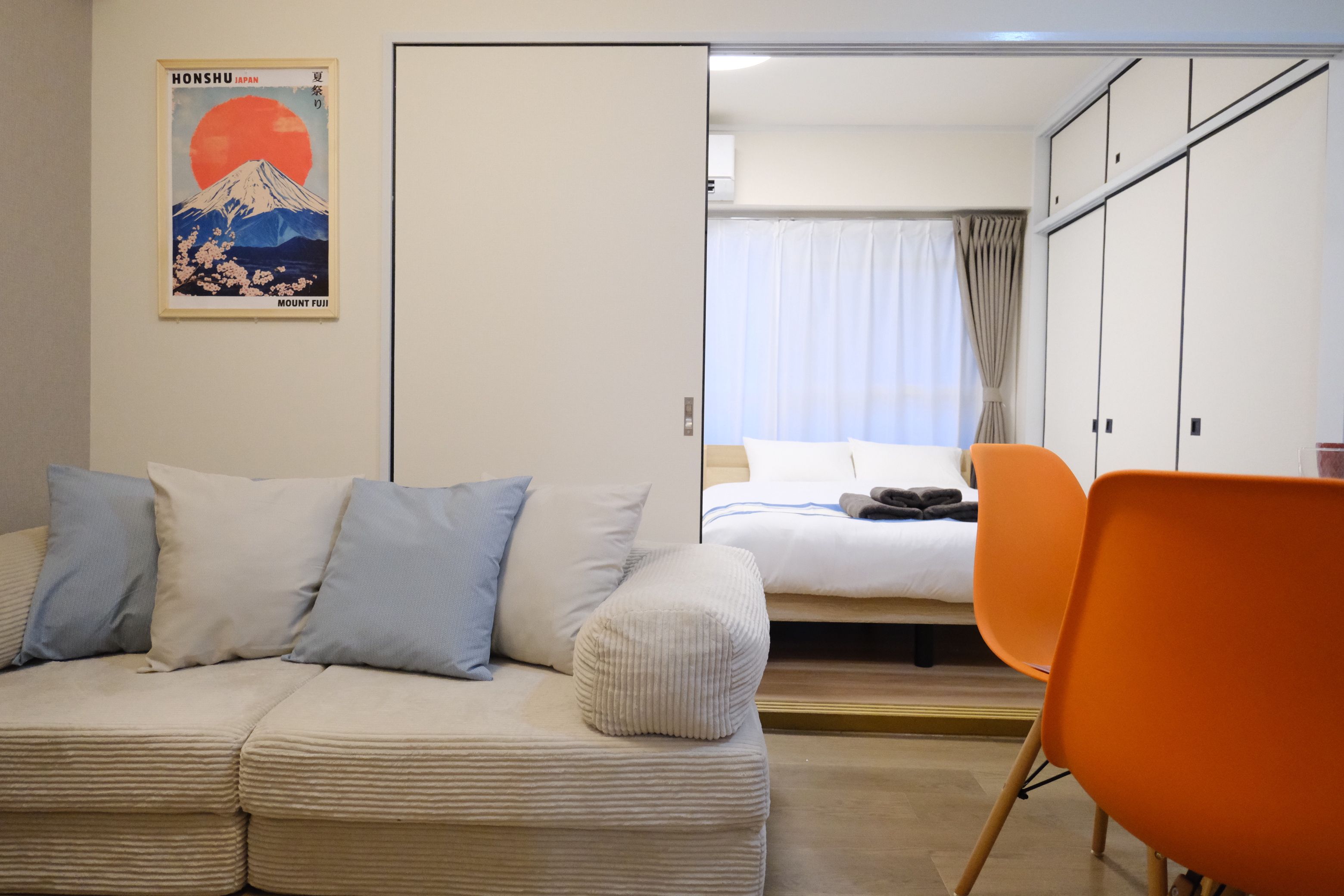 A hotel room with a bed, a sofa, and a chair. There is a poster on the wall.