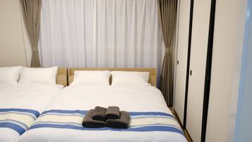 A hotel room with a large bed, two pillows, a folded towel, and a wardrobe.
