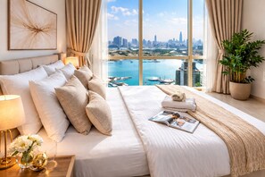 A hotel room with a large bed, a view of a cityscape and water, and a potted plant. - 1BR Apartment - Stunning Sea Views - Pool & Gym - Al Reem Island (Abu Dhabi)