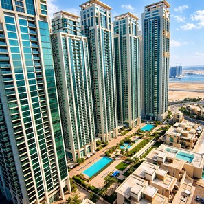 A high-rise residential building complex with multiple balconies, a swimming pool, and a view of the beach. - 1BR Apartment - Stunning Sea Views - Pool & Gym - Al Reem Island (Abu Dhabi)