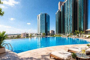 Une piscine avec des chaises longues et une vue sur la ville en arrière-plan.