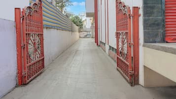 A narrow alleyway with red metal gates on both sides, leading to a building with a striped awning.