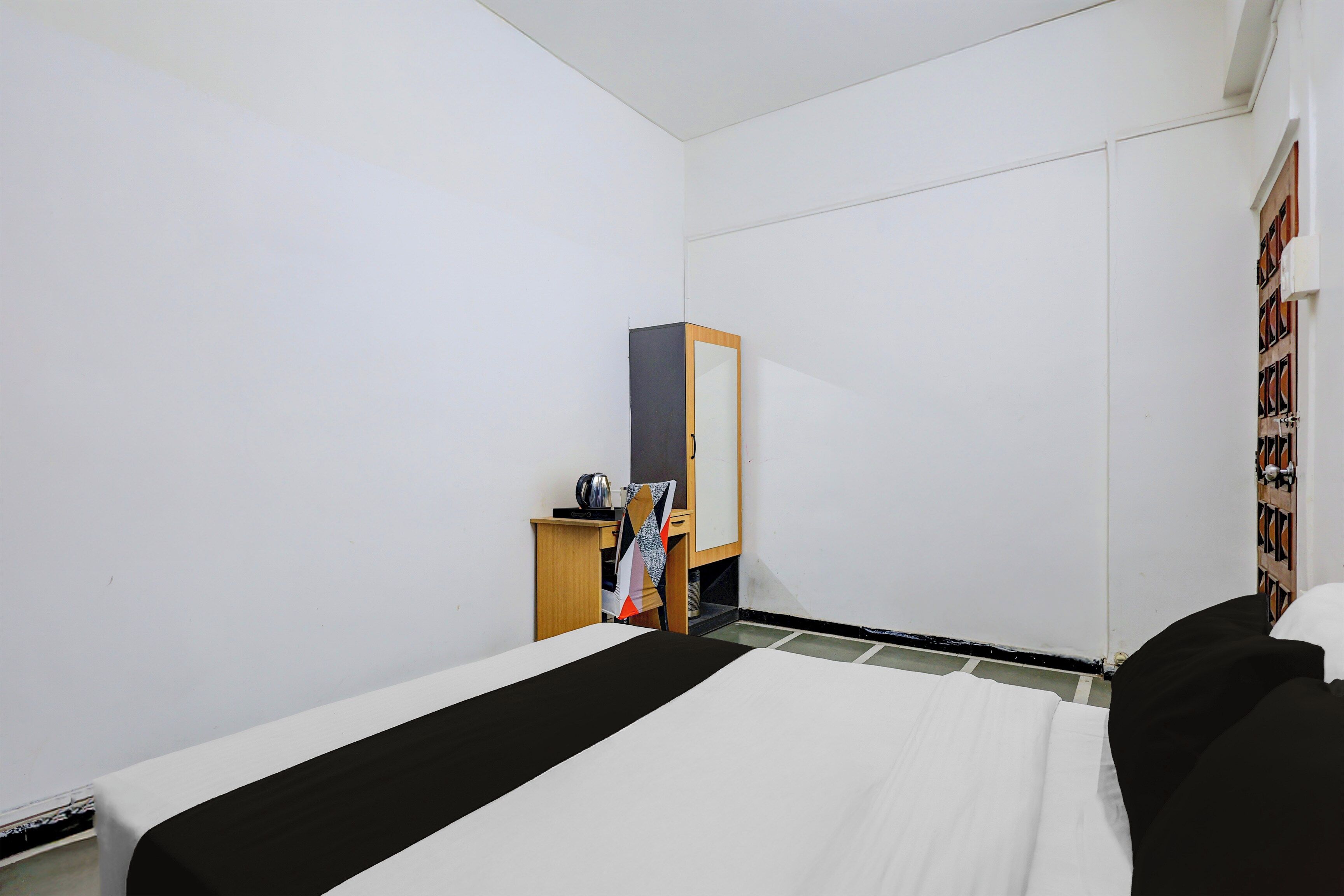 Quarto com cama, armário de madeira, espelho e porta com vidro decorado.