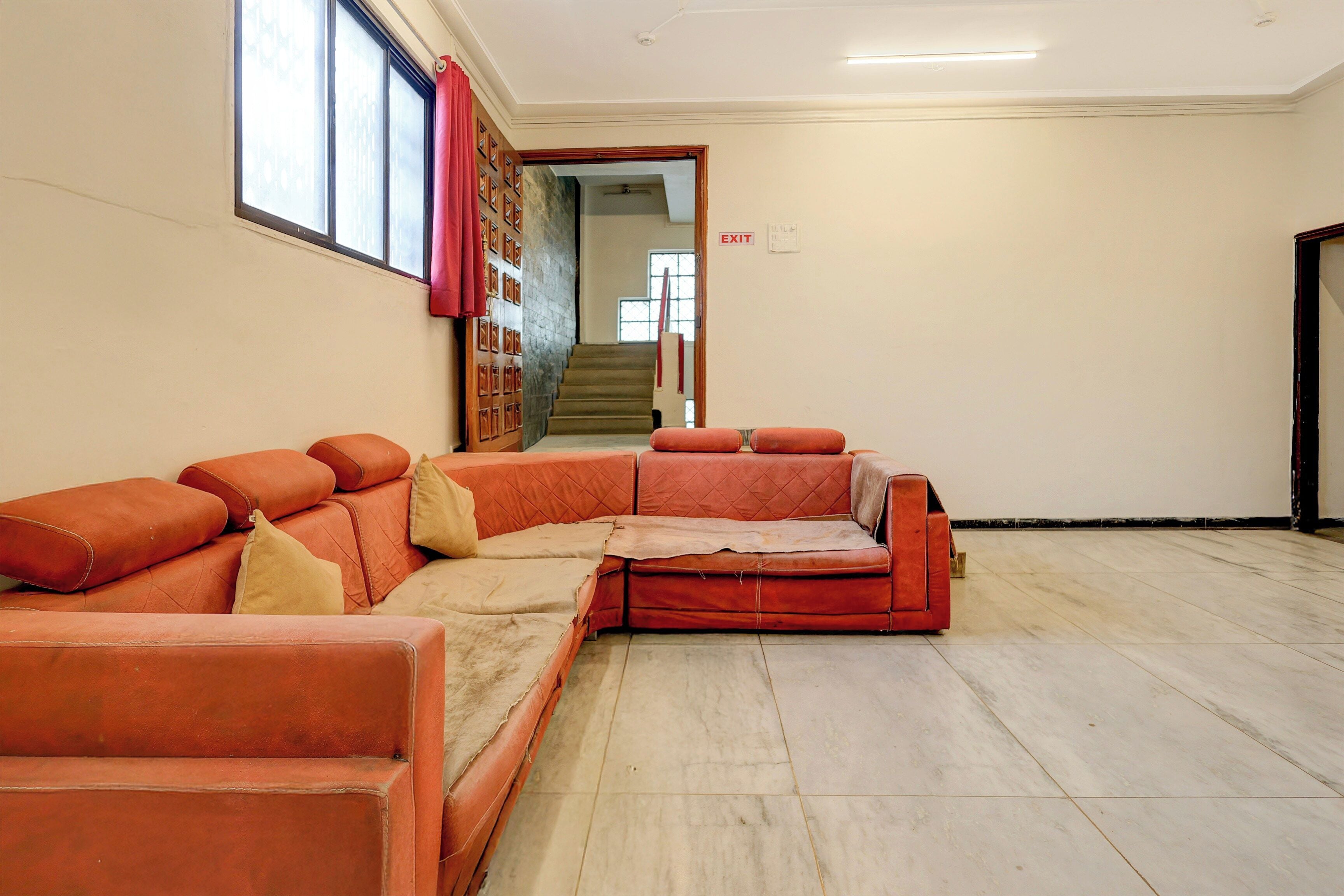 Una habitación con sofá seccional, una escalera y una señal de salida.