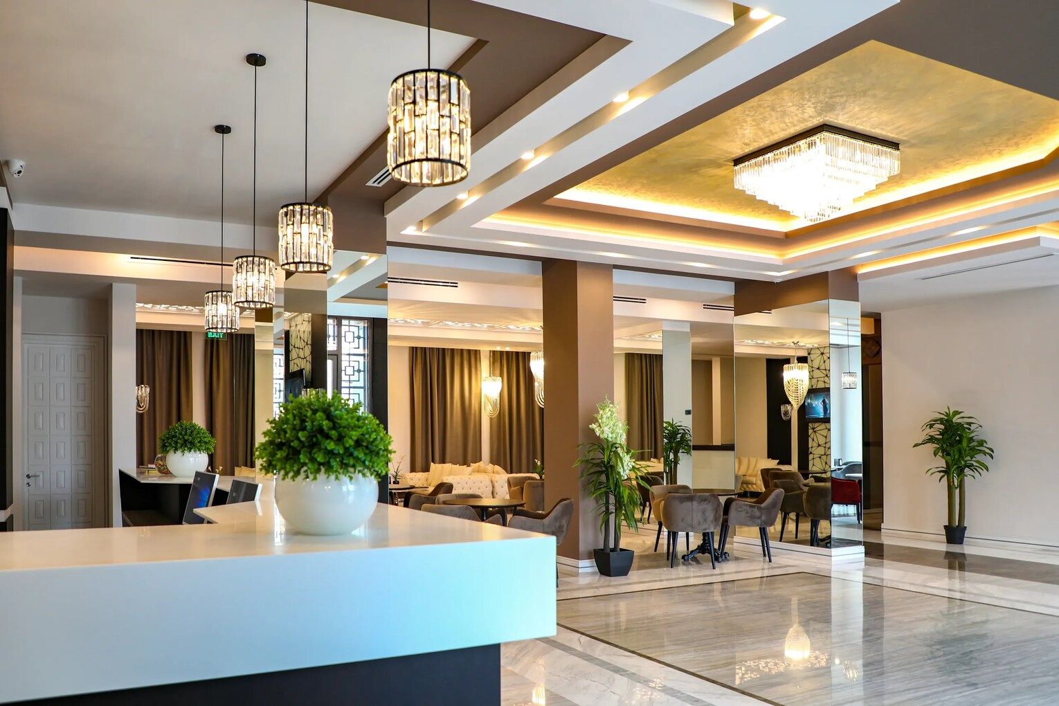 Un moderno vestíbulo de hotel con mostrador de recepción, zona de estar e iluminación decorativa.