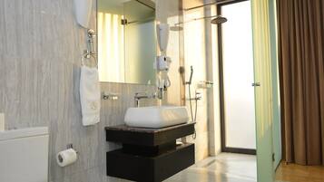 Un baño moderno con un lavamanos blanco, un espejo, un perchero para toallas y una zona de ducha.