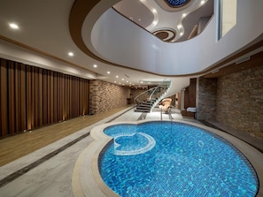 Una piscina interior moderna con diseño circular, una escalera y una pared de madera.