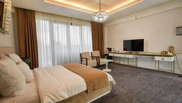 Una habitación de hotel con una cama, un escritorio con televisor, una silla y una mesita.