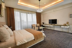 Una habitación de hotel con una cama, un escritorio con televisor, una silla y una mesita.