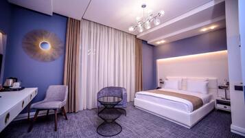Une chambre d’hôtel moderne avec un grand lit, un bureau, une chaise et une petite table.
