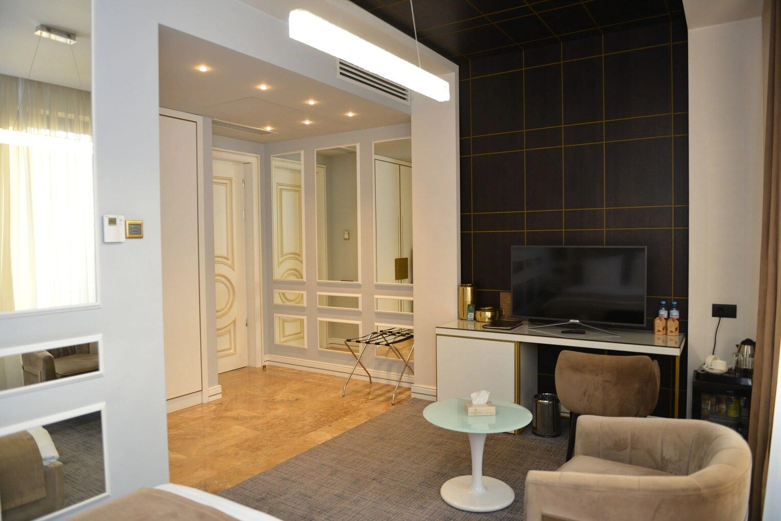 A hotel room with a TV, seating area, and a small table.