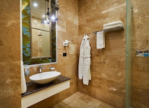 A bathroom with a large mirror, a sink, a towel rack, and a shower area.
