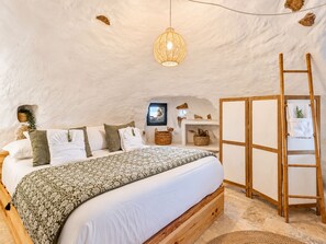 Et hyggeligt soveværelse med en stor seng, en hængende lampe og en træstige.