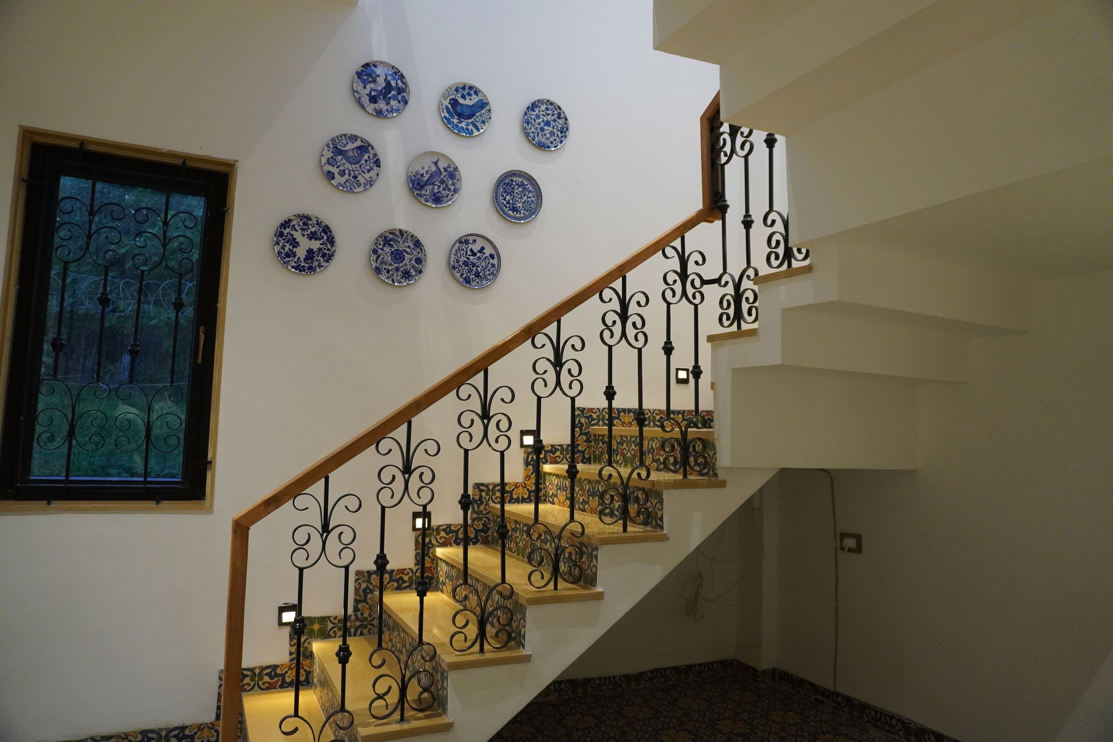 A staircase with ornate metal railings and a series of decorative plates on the wall.