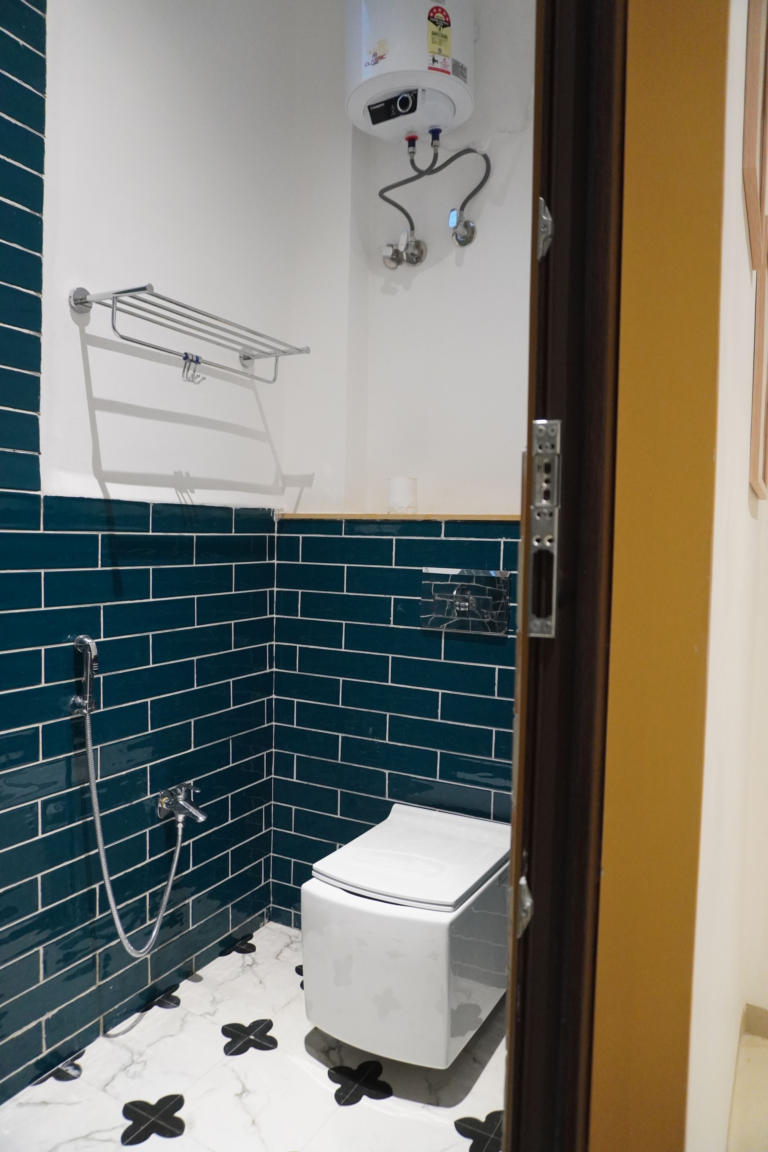 Un baño con paredes de azulejos azules, un inodoro blanco, una ducha y un perchero para toallas.