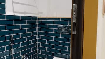Un baño con paredes de azulejos azules, un inodoro blanco, una ducha y un perchero para toallas.