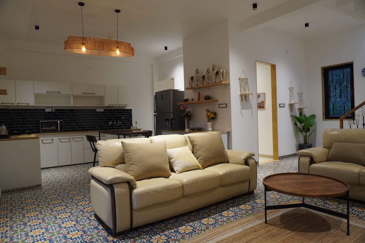 Una sala moderna con un sofá color beige, una mesa de centro de madera y un suelo estampado.