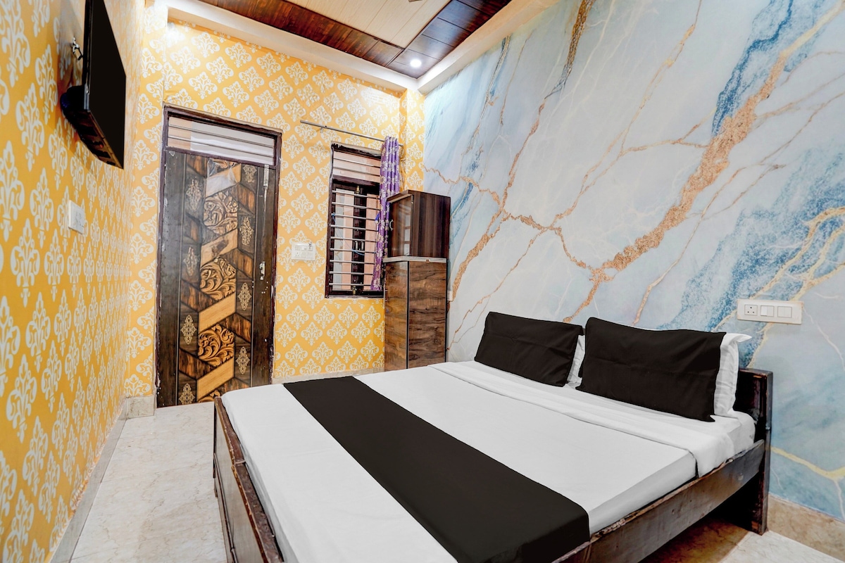 Une chambre à coucher avec un lit, une armoire, un téléviseur et un mur décoré d’un motif.