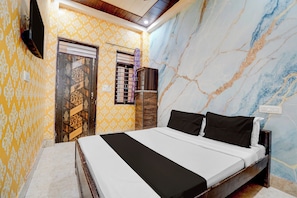 Une chambre à coucher avec un lit, une armoire, un téléviseur et un mur décoré d’un motif.
