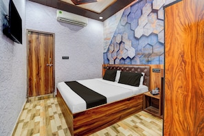 Une chambre d’hôtel avec un lit en bois, un téléviseur fixé au mur et un motif décoratif sur le mur.