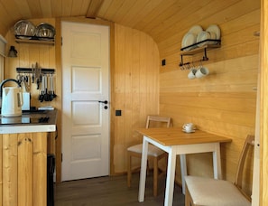 Eine kleine Küche mit weißer Tür, Holzvertäfelung und einem Essbereich mit Tisch und Stühlen.