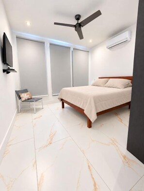 A bedroom with a bed, a chair, a ceiling fan, and an air conditioning unit. - Blue Wave House I Ocean Villas (Playas Del Coco)