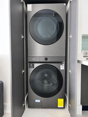 A compact, modern laundry room with two stacked washing machines. - Blue Wave House I Ocean Villas (Playas Del Coco)