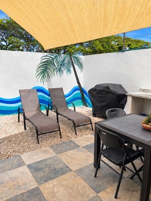 An outdoor patio with a table, chairs, a grill, and a wall mural. - Blue Wave House I Ocean Villas (Playas Del Coco)