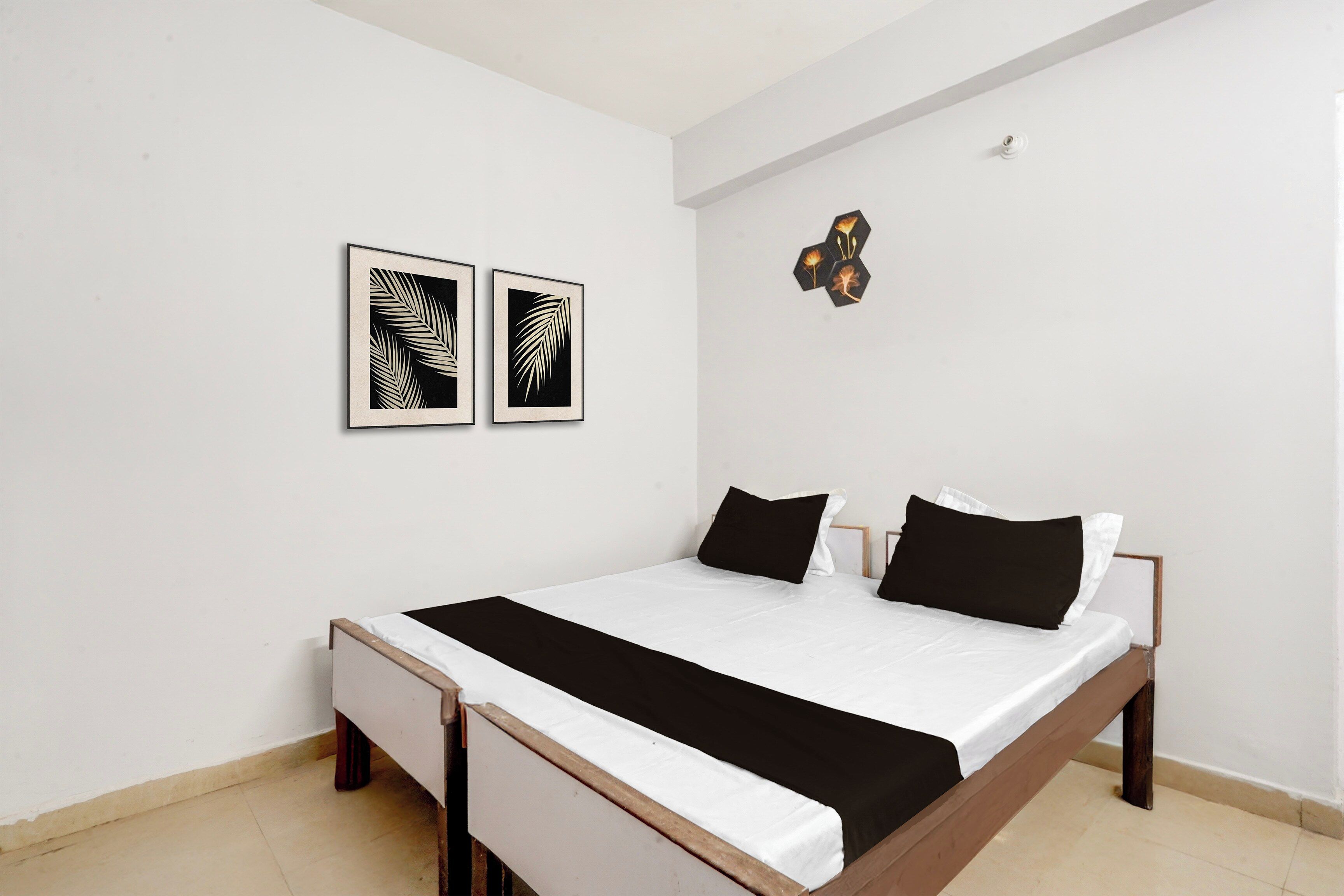 Un dormitorio con una cama, dos cuadros enmarcados y un pequeño adorno en la pared.