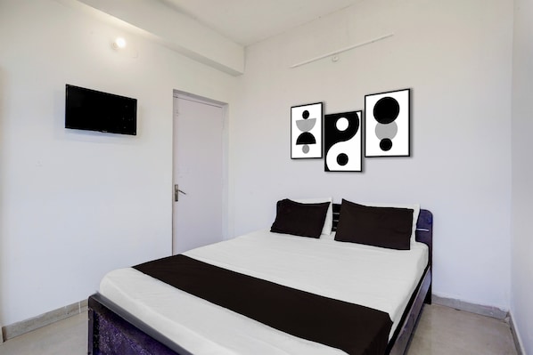 Un dormitorio con una cama, una puerta y tres cuadros en la pared.