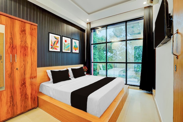 A modern bedroom with a large bed, wooden wardrobe, and a large window with a view of greenery.