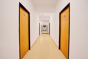 Un pasillo con puertas numeradas 21 y 208, que conduce a un vestíbulo con suelo de baldosas y paredes blancas.