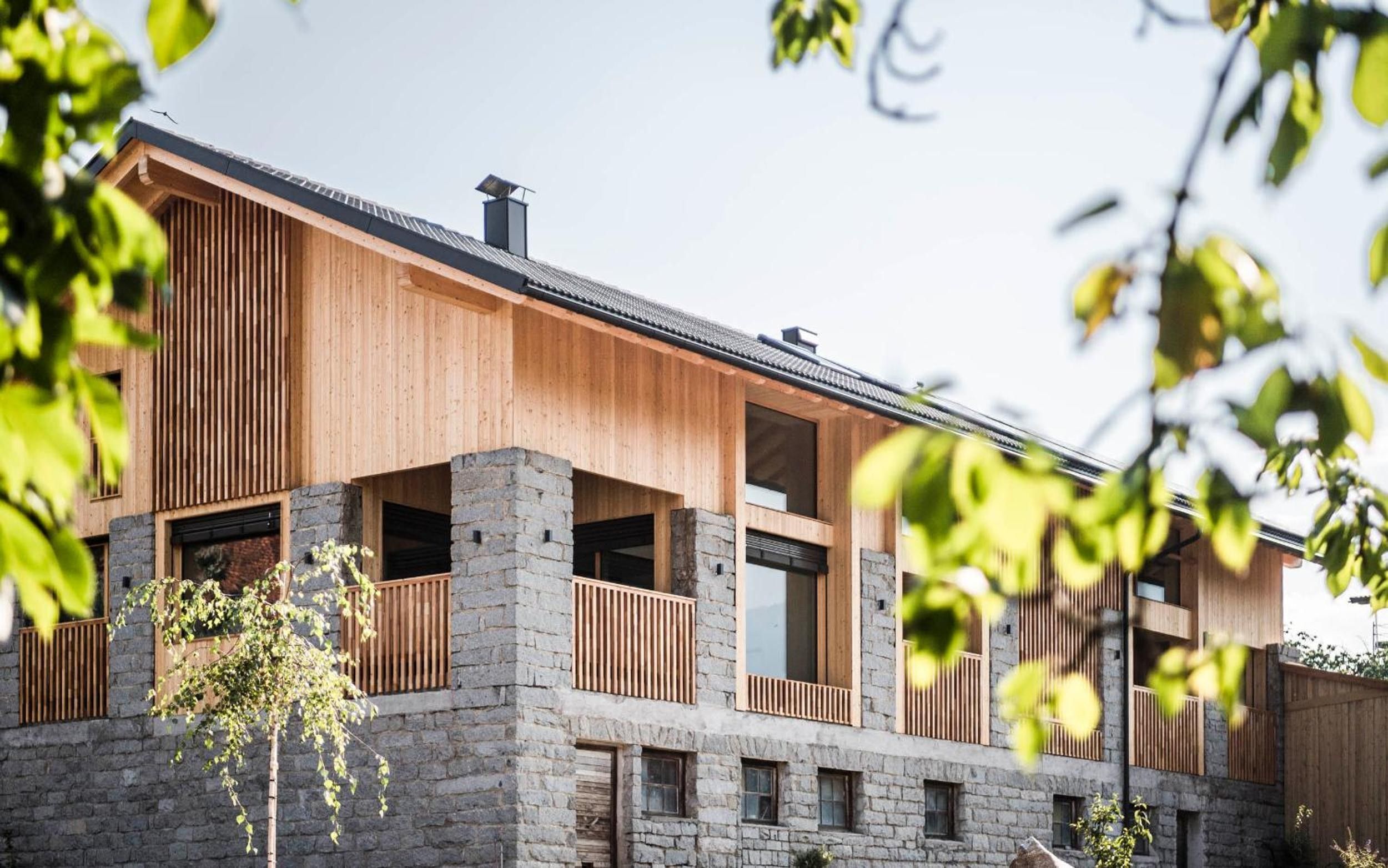 A modern two-story building with a stone facade and wooden balconies.