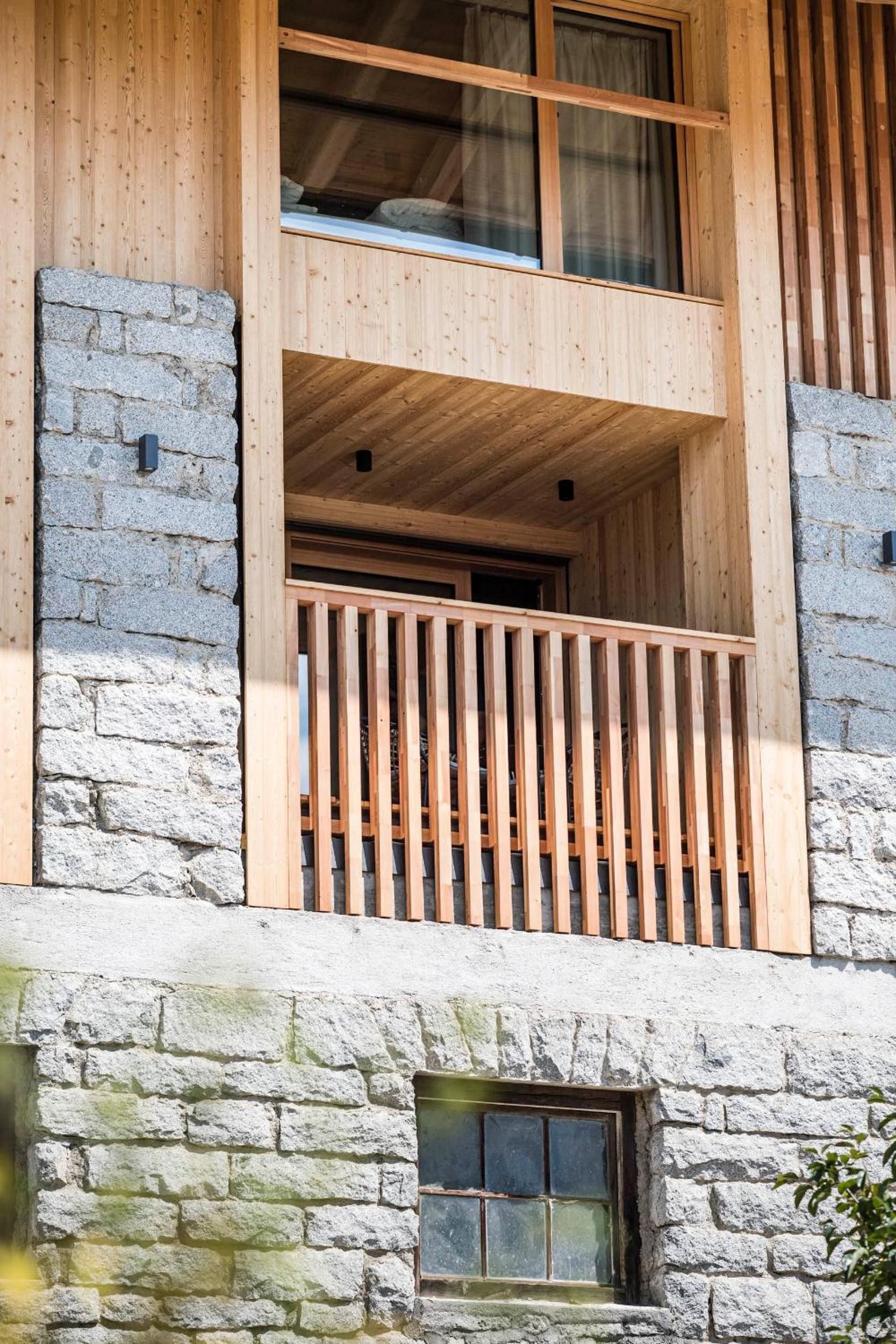 Un edificio de varios pisos con fachada de piedra, balcones de madera y una ventana pequeña.