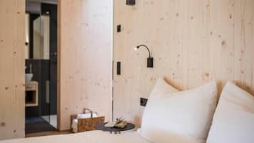 A bedroom with a wooden wall, a bedside table with a book, and a white bed.