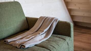 A room with a green sofa and a knitted blanket.
