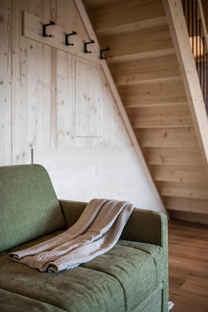 Una habitación con un sofá verde y una manta tejida.