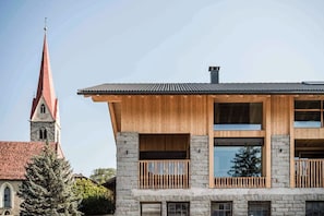 Un edificio moderno de dos pisos con fachada de madera, ventanas amplias y base de piedra.