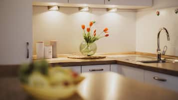 A kitchen with white cabinets, a stainless steel sink, and a vase with orange flowers on the counter.