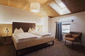 A bedroom with a bed, a chair, a nightstand, a lamp, a window with curtains, and a skylight. - Apartment 'Töllhof Studio - Bauernstube' with Mountain View and Wi-Fi (Rasa)