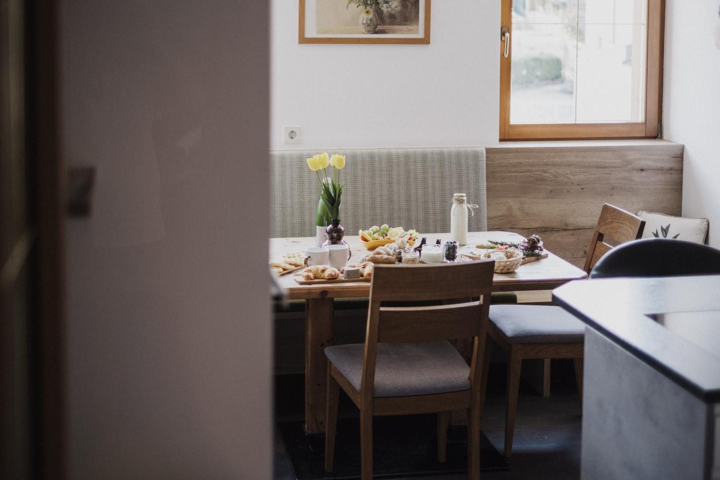 Ein Essbereich mit einem für das Frühstück gedeckten Tisch, einschließlich Croissants und einer Blumenvase.