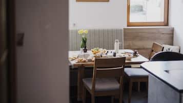 Ein Essbereich mit einem für das Frühstück gedeckten Tisch, einschließlich Croissants und einer Blumenvase.