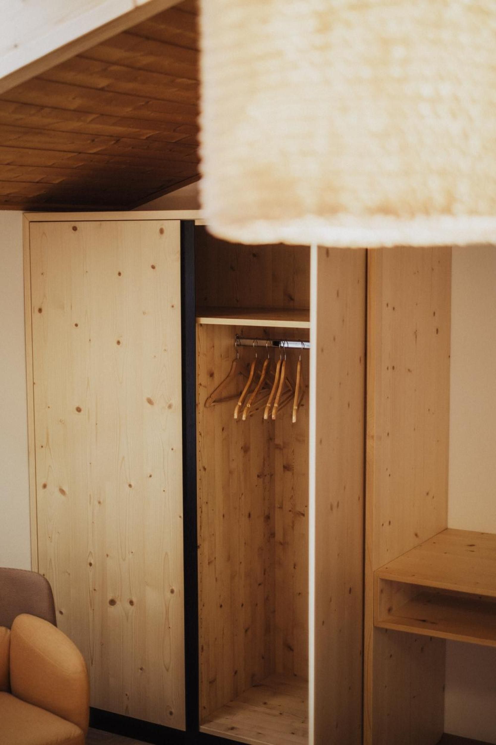 Un armario de madera con espacio para colgar y un banco.