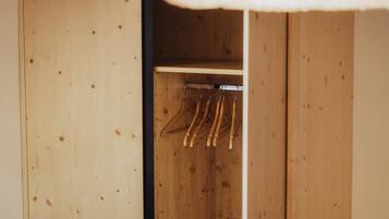 Un armario de madera con espacio para colgar y un banco.